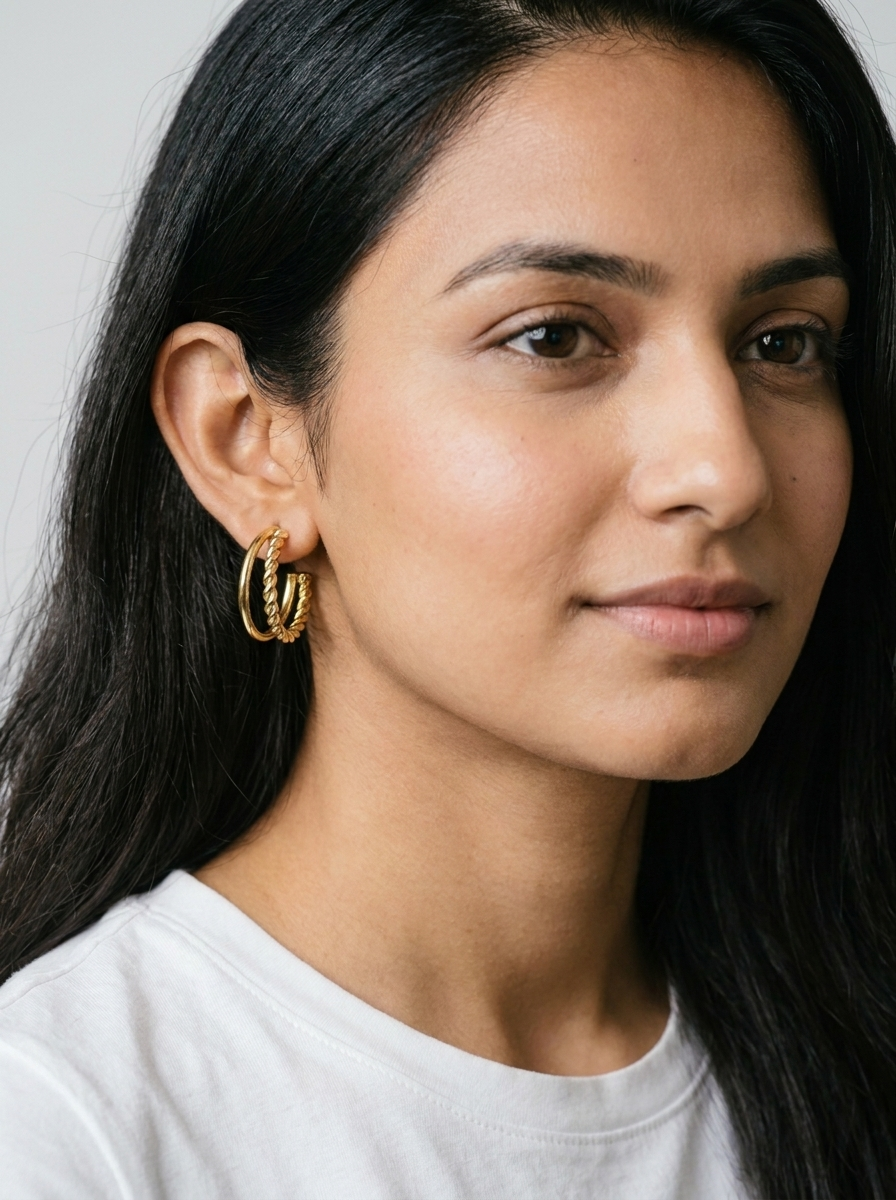 Gold double hoop earrings with rings on linen with dried flowers and rose petals
