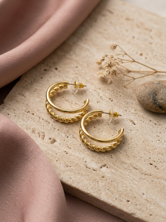 The Double Hoops gold earrings flatlay with tag on cream linen with eucalyptus and pearls