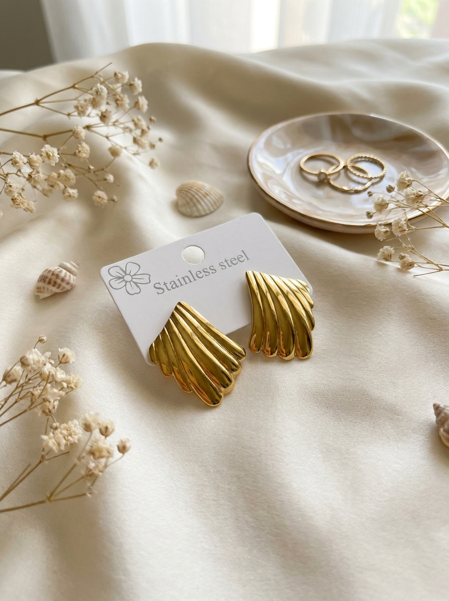 The Shell Studs gold stud earrings on packaging card with seashells and dried flowers