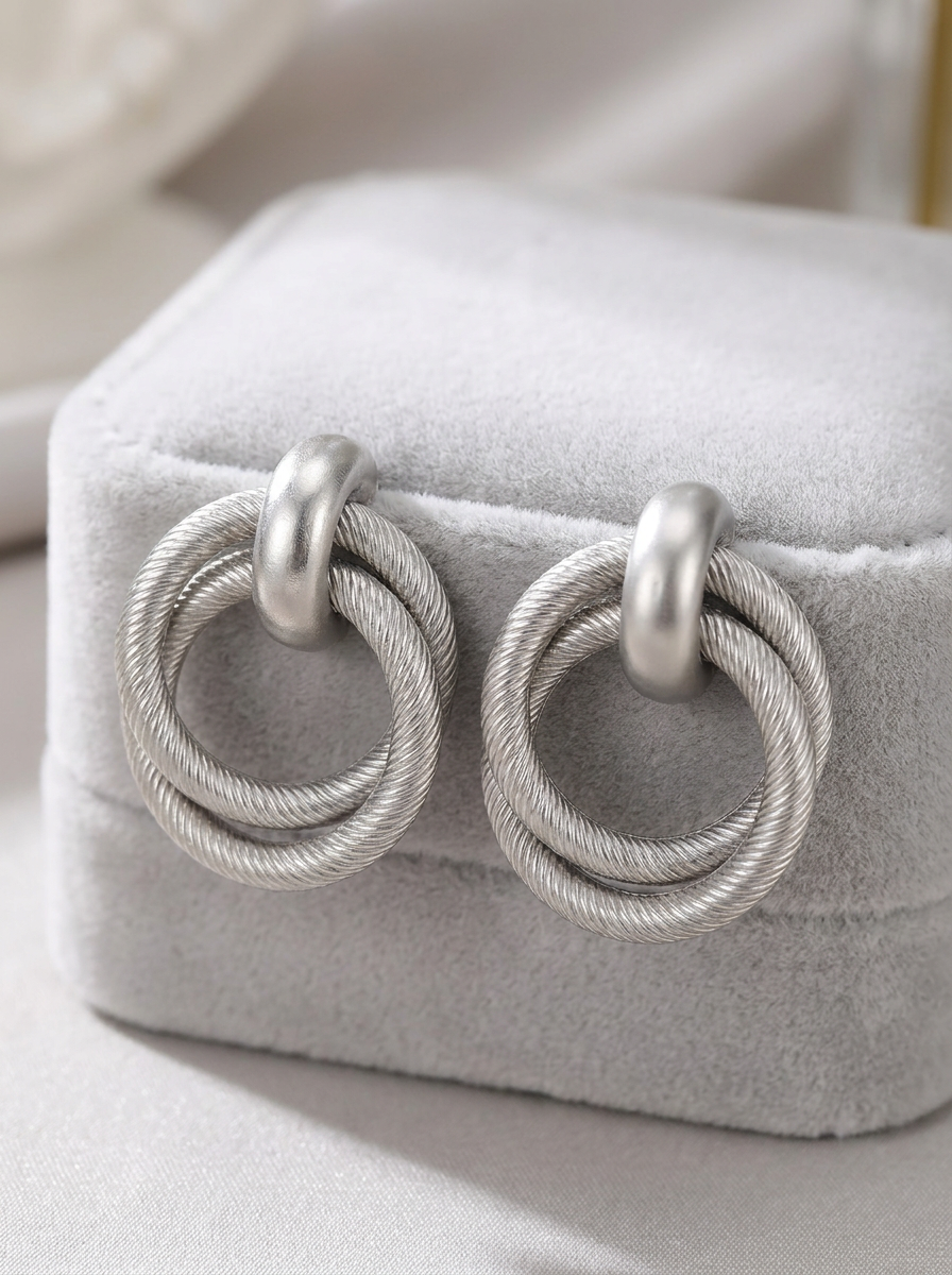Silver twisted double hoop earrings on white velvet jewellery box