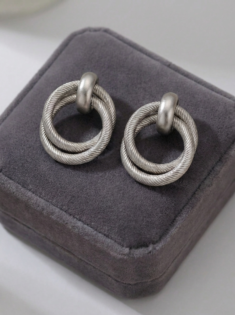 Silver twisted double hoop earrings on grey velvet jewellery box