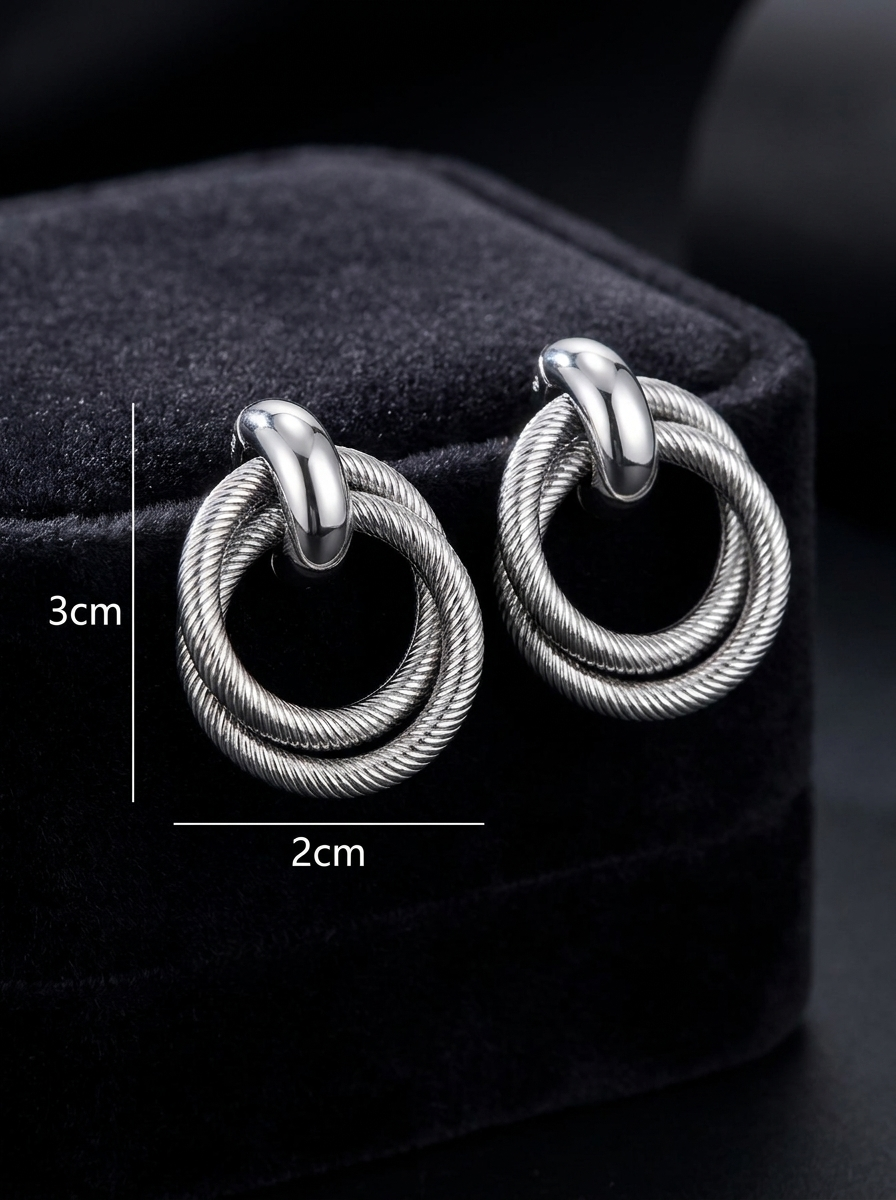 Gunmetal twisted double hoop earrings close-up on dark grey velvet box