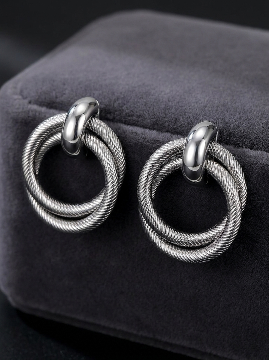 Gunmetal twisted double hoop earrings on grey velvet fabric close-up